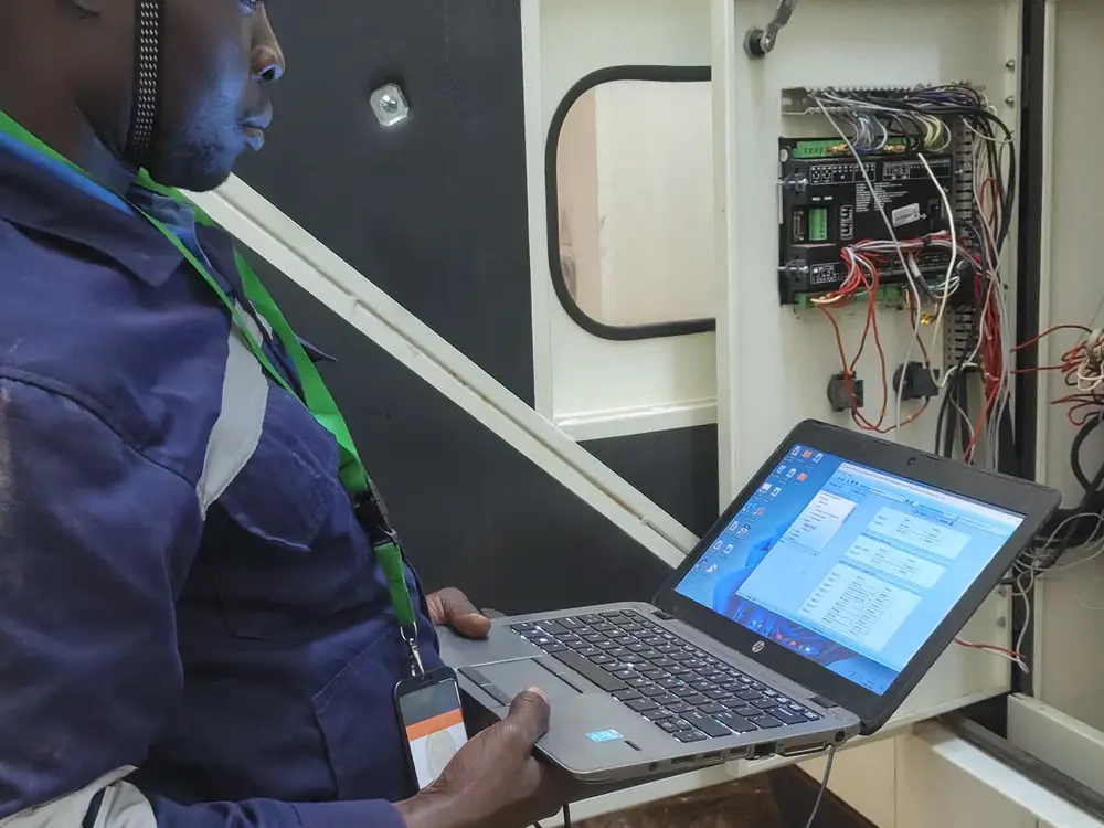 Engineer diagnosing a generator controller with a laptop